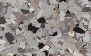 A close-up view of a gray, beige, and black epoxy flooring with scattered irregular color flakes.